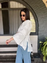Blusa blanca de algodón con bordado tipo broderie, escote en V y mangas 3/4.