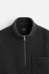 Sudadera gris oscuro de tejido polar con lana, corte relaxed fit, cuello alto con cierre de cremallera, manga larga, bolsillo tipo parche en el pecho y terminaciones elásticas.