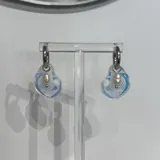 Aros colgantes con argolla de acero quirúrgico hipoalergénico y dije con forma de ostra con diseño de olas en color celeste y perla de río natural.