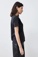 Remera negra de manga corta con apliques bordados en el escote.
