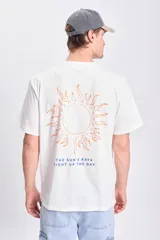 Remera de manga corta color crudo, corte oversize, con estampa de un sol y la frase 'The sun's rays light up the day' en la espalda.