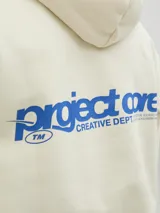 Buzo con capucha color crema, de manga larga y corte holgado. Tiene bolsillo tipo canguro y logo estampado en el pecho.