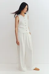 Pantalón culotte color blanco hueso, de tiro alto con cintura elástica, corte amplio y bolsillos laterales.
