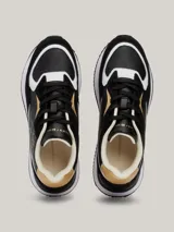 Zapatillas deportivas Tommy Hilfiger de piel negra con paneles con monogramas TH en relieve y detalles en blanco y dorado.