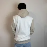 Canguro con capucha color marrón y beige, con logo bordado en el pecho y bolsillo tipo canguro.