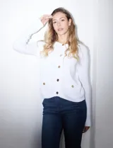Cardigan tejido negro con escote redondo y abertura frontal con botones dorados. Tiene bolsillos simulados en la parte delantera.