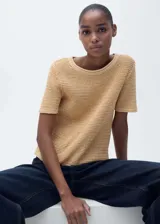 Remera de punto color beige, de manga corta y cuello redondo.