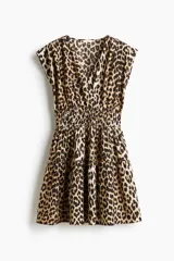 Vestido corto sin mangas en tejido fresco de algodón con estampado animal print. Modelo con escote cruzado en V, pliegues en los hombros, cintura fruncida y pollera con vuelo.