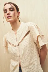 Camisa color crema de algodón liviano con diseño calado, cuello mao y mangas cortas con volados.