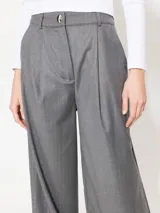 Pantalón sastrero gris con lurex, taba y bota ancha. Acceso por cierre, broche niquel personalizado y botón interno. Bolsillos traseros falsos y cintura con presillas.