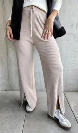 Pantalón de punto beige con textura acanalada, corte palazzo, cintura alta con cordón ajustable y aberturas con cierre en los tobillos.