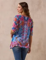 Blusa de modal estampado con flores en tonos azules, rosas y amarillos, marca Ruby Rd. Tiene cuello redondo, manga corta con abertura y apliques de brillos en el frente.