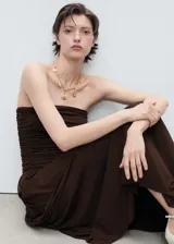 Vestido largo marrón sin mangas, con escote strapless, detalle fruncido en la cintura y falda acampanada.