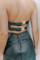 Falda midi de cuero ovino color verde azulado con efecto desgastado. Presenta tajo lateral con cordones cruzados.