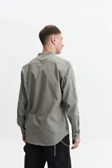Camisa azul de manga larga con cuello mao y cartera abotonada.