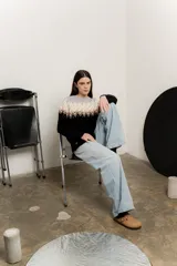Sweater de punto con cuello redondo, mangas largas y diseño de guardas geométricas en tonos gris, beige y blanco en la parte superior, y negro en la parte inferior.