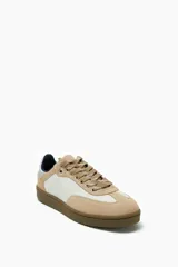 Zapatillas deportivas bajas color beige y blanco, con cordones y suela marrón.