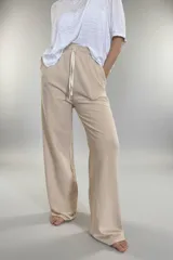 Pantalón de jersey color beige, de corte amplio, con bolsillos laterales y cintura elastizada con cordón ajustable.
