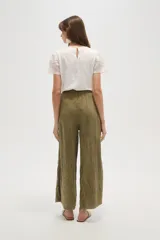 Pantalón ancho de algodón negro, con cintura ajustable mediante cordón y bolsillos laterales. Presenta una textura arrugada o plisada.