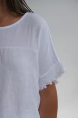 Remera blanca de lino italiano, con escote redondo y mangas cortas con detalle desflecado. Corte amplio y holgado.