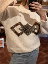 Sweater color crema de tejido de punto con cuello redondo y apliques geométricos metálicos bordados a mano en el frente.