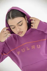 Buzo con capucha color rosado con la palabra "Pulau" estampada en el frente con letras delineadas en color naranja.