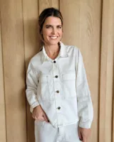 Sobrecamisa blanca de denim con cuello camisero, cierre frontal con botones marrones, mangas largas y bolsillos de parche en el pecho.