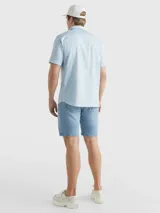 Camisa celeste de mangas cortas, confeccionada en popelín de puro algodón. Tiene cuello abotonado, bajo redondeado y logo de Tommy Hilfiger bordado en el pecho.