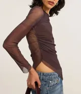 Blusa de manga larga confeccionada en tule color marrón con estampado abstracto. Presenta escote asimétrico, transparencia en mangas y espalda, fruncido lateral y bajo asimétrico.