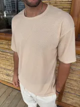 Remera color beige de punto con cuello redondo y mangas cortas. Corte holgado.