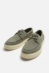 Zapato náutico de cuero color azul marino con cordones finos y suela plana.