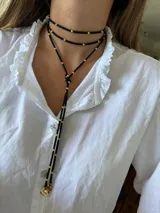 Corbatín negro con detalles en dorado, diseñado para llevar alrededor del cuello.
