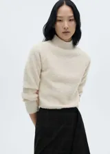 Sweater color crema de tejido bouclé, con cuello perkins y mangas largas.