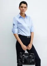 Camisa de algodón azul, con cuello camisero, mangas largas y puños abotonados, confeccionada en popelín con diseño recto.