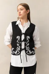 Chaleco blanco de algodón con bordados de cadenas doradas y lazos frontales.