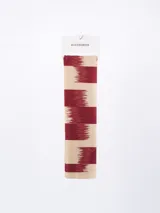 Pañuelo rectangular con estampado abstracto en tonos terracota, negro, blanco y beige.