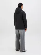 Campera softshell negra con capucha ajustable con cordón, mangas largas con puños de canalé, cierre frontal con cremallera y bolsillos delanteros. Forro sin relleno y costuras cubiertas.