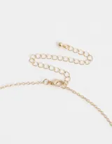Collar corto dorado con cadena de eslabones y dijes colgantes: corazón calado, luna esmaltada celeste, strass y dije ovalado esmaltado con arcoíris.