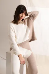 Sweater tejido color crema con mangas ranglán color beige y cuello redondo.