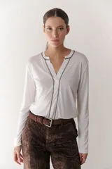 Remera blanca de mangas largas con escote en V y costuras decorativas en negro.
