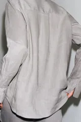 Camisa de lino color verde oliva, con cuello solapa, manga larga con puños y cierre frontal con botones.