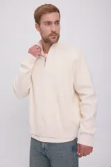 Sweater de punto color crema, con cuello alto y cierre de cremallera parcial.