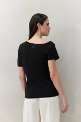 Top tejido azul marino de silueta ajustada con diseño minimalista y escote asimétrico, adornado con pequeños botones metálicos.