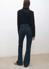 Pantalón de jean azul oscuro, de tiro alto, corte flare y cinco bolsillos.