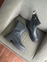 Bota corta color verde militar, con caña media, suela track y elástico lateral.