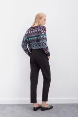 Pantalón negro de tiro alto con elástico interno en la cintura, botones falsos y terminación con volado. Tiene bolsillos aplicados en delantero y falsos en espalda.