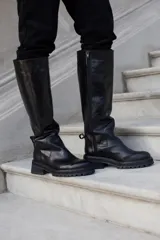 Bota alta de cuero color negro con puntera marrón, caña alta y suela track.