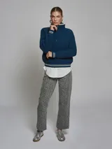 Sweater color crema de tejido grueso con medio cierre, cuello alto y detalles deportivos con rayas negras en puños y hombros.