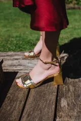 Sandalias plateadas de cuero con tiras entretejidas en el empeine, pulsera al tobillo con hebilla y tacón cuadrado. Marca Fiore.