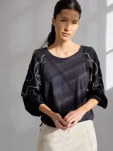 Remera gris de algodón con mangas color beige con bordados de líneas en blanco, amarillo y gris.